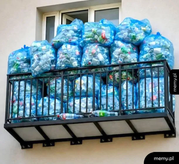 Balkon z dużą ilością niebieskich worków wypełnionych plastikowymi butelkami.