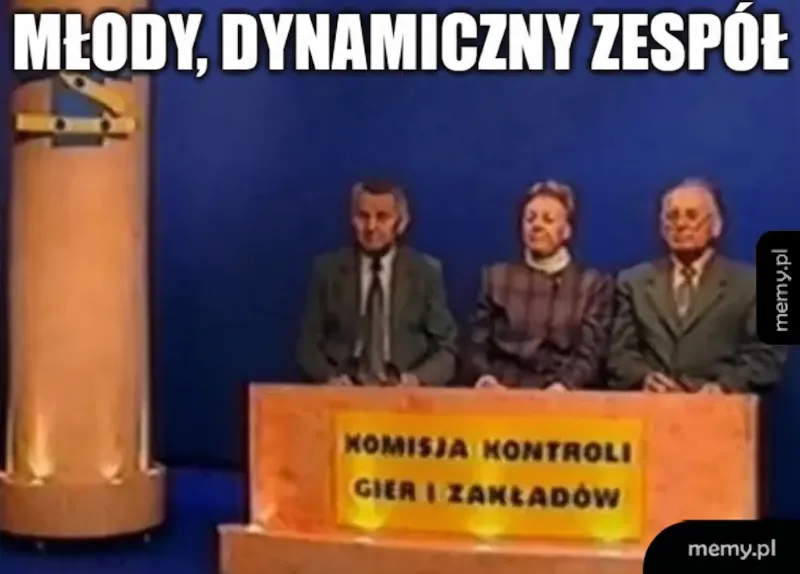 Trzy osoby siedzące przy biurku w studiu telewizyjnym.