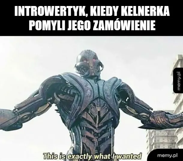 Robot z rozłożonymi ramionami w miejskim otoczeniu.