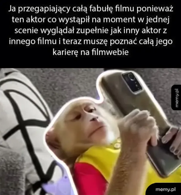 Małpa leżąca i przeglądająca coś w smartfonie.