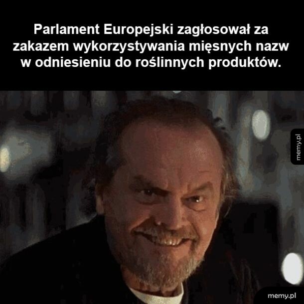 Mężczyzna z zarostem uśmiechający się złowrogo w ciemności.