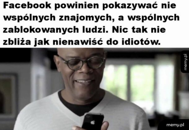 Mężczyzna w okularach patrzy w telefon z uśmiechem.